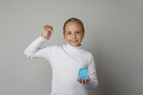 Young girl holding Invisalign tray
